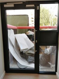 Construction offcuts and packaging awaiting clearance behind glazed doors